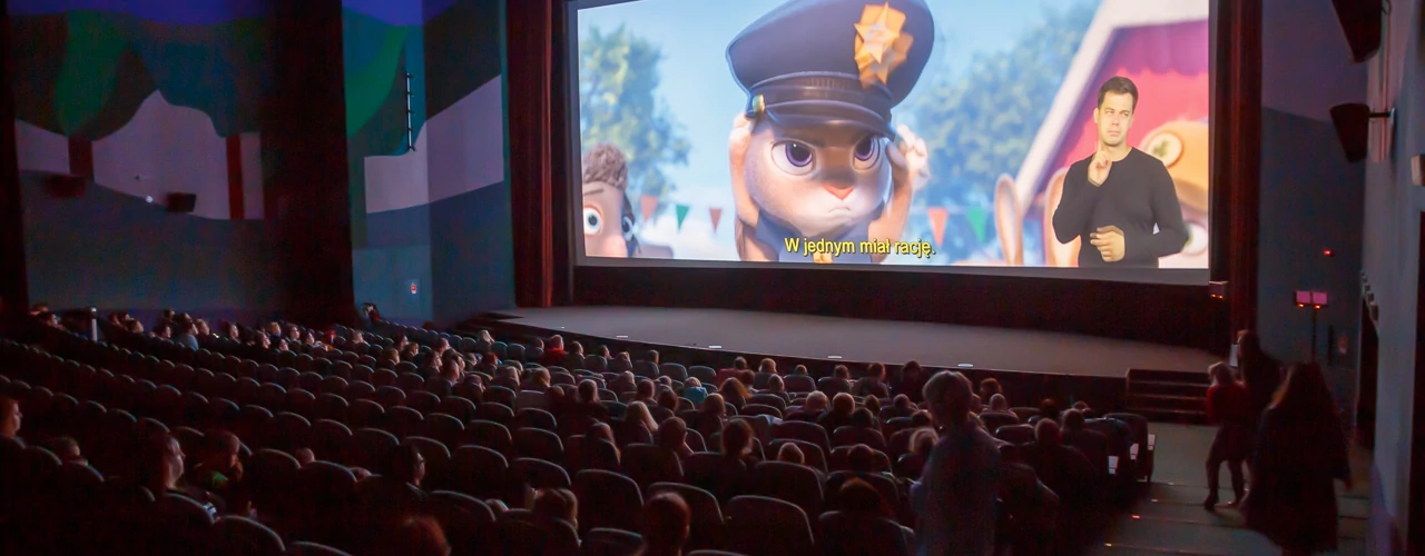 Sala w kinie Kijów. Projekcja filmu Zwierzogród. Na widowni kilkuset widzów - głównie dzieci. W prawym dolnym rogu ekranu - tłumacz PJM.